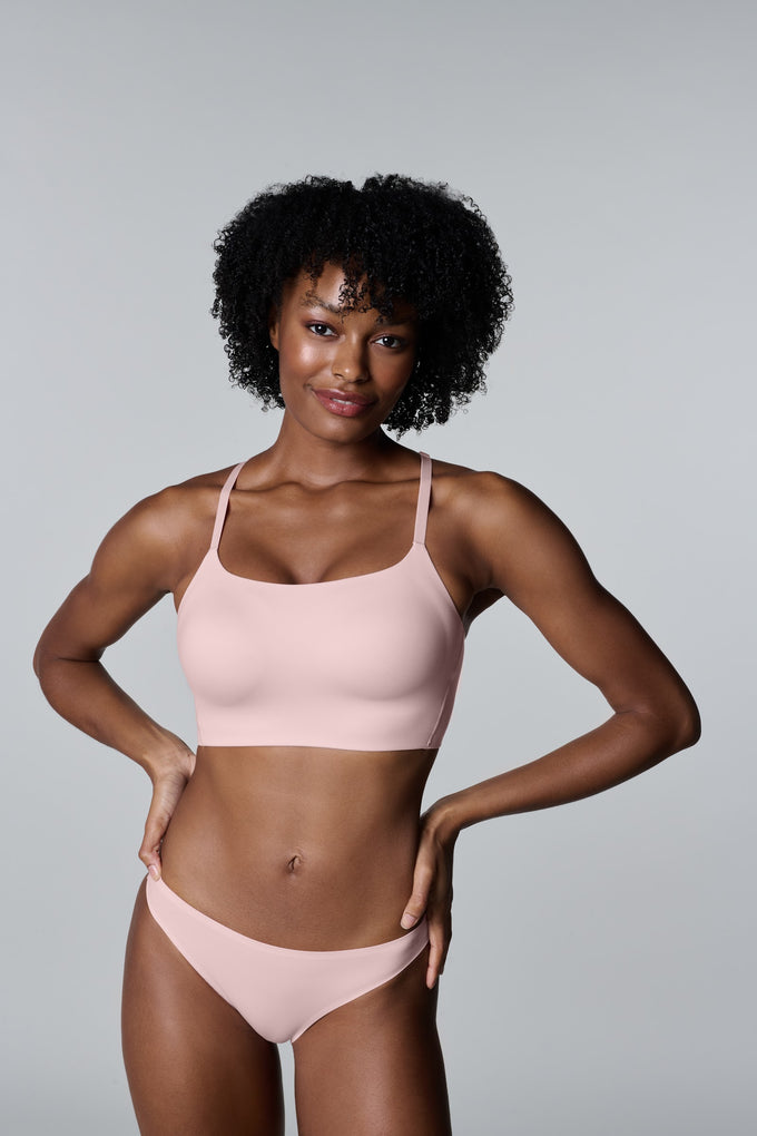 Model with hands on her hips wearing the Daily Racerback in Camellia, a wire-free bra with a square scoop neckline