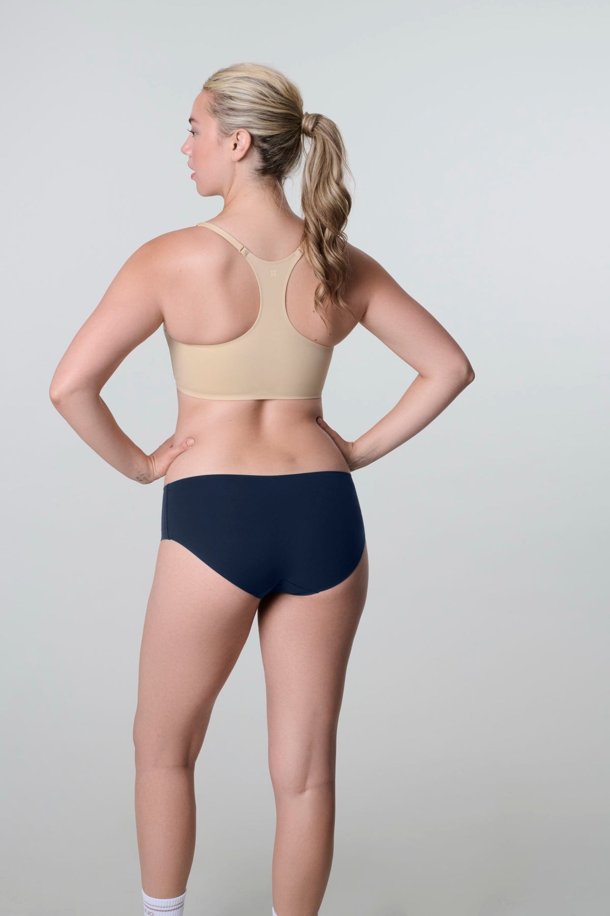 Daily Hipster in Navy, back view worn by a woman with hands on her hips, showing the full-coverage fit