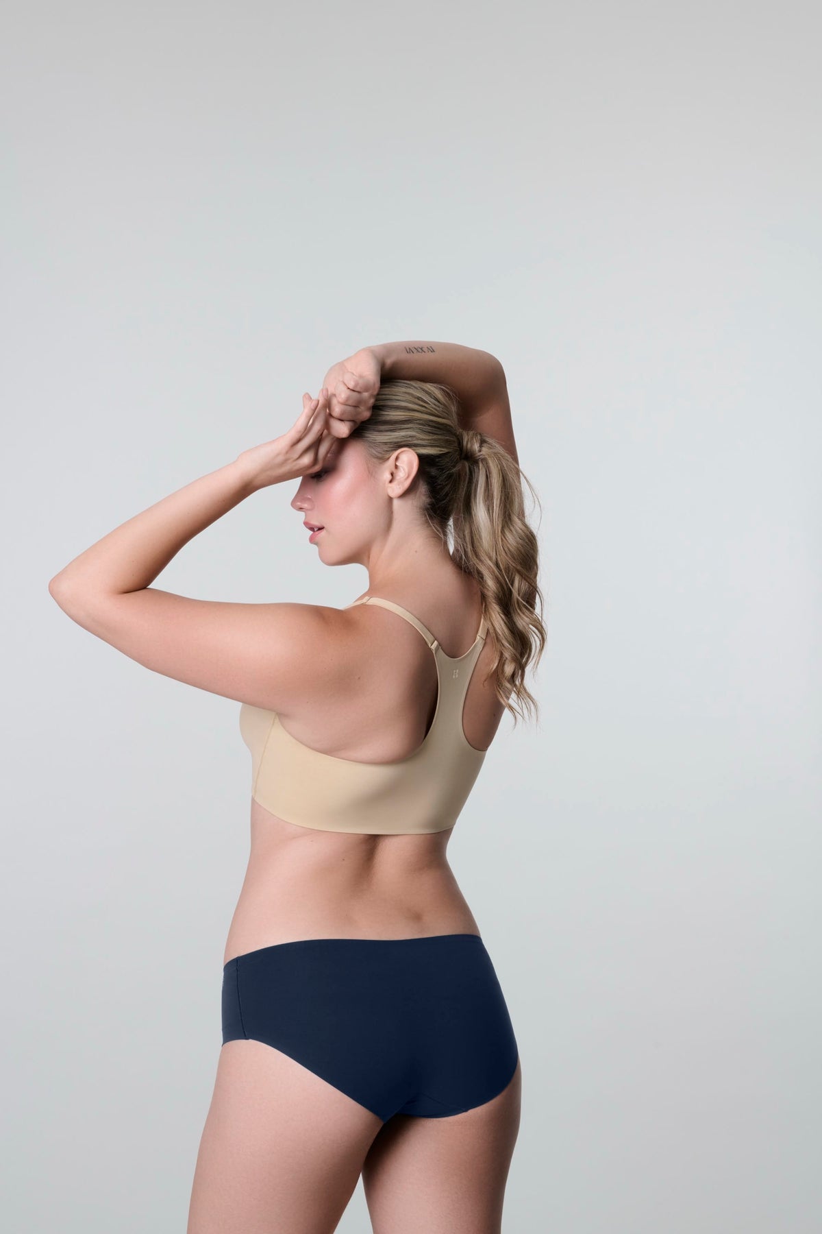 Daily Hipster in Navy, back view worn by a woman with both arms raised to her head, showing the seamless rear coverage