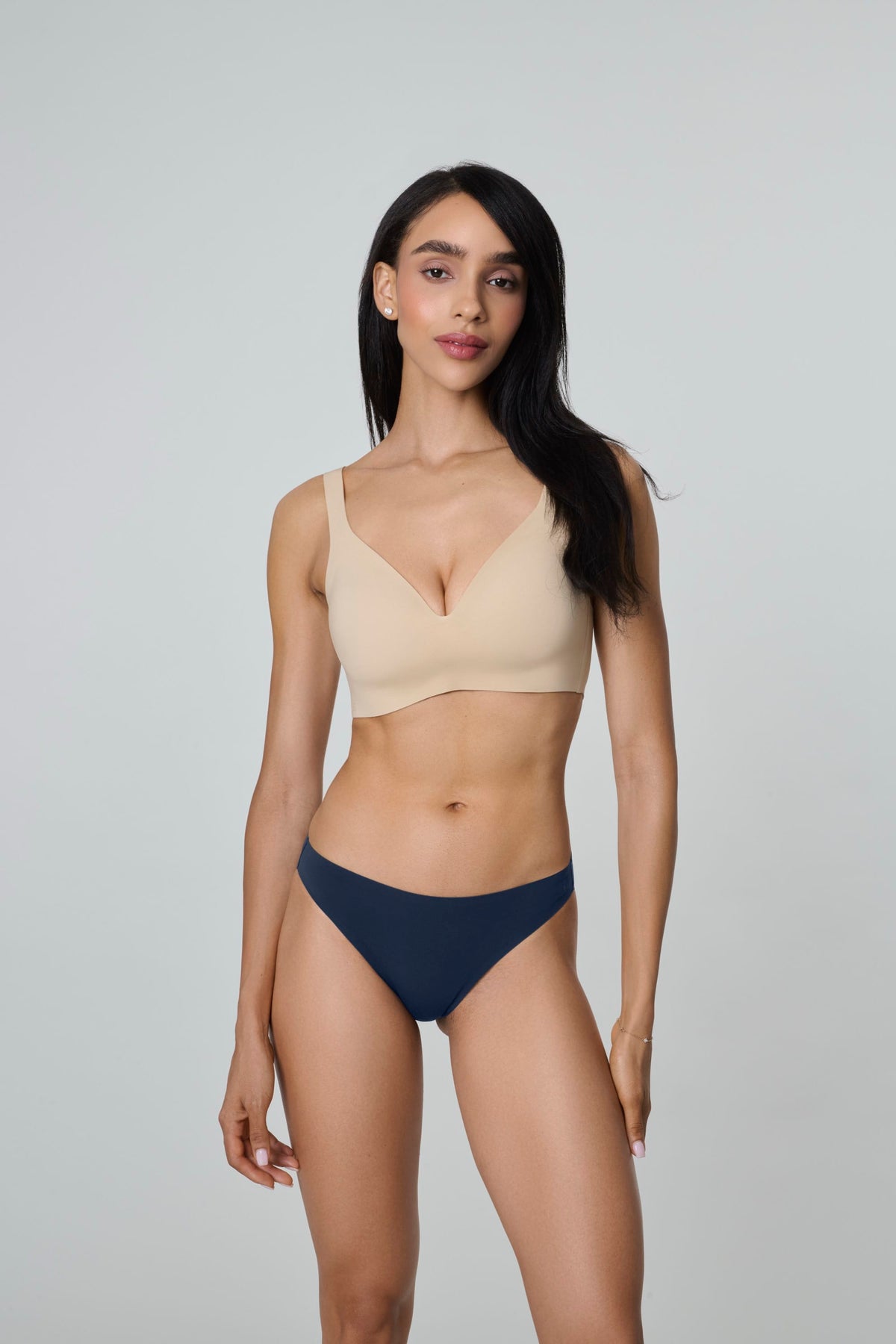 Daily Bikini in Navy, front view worn by a woman with long dark hair standing with arms at her sides, with a nude plunge bra