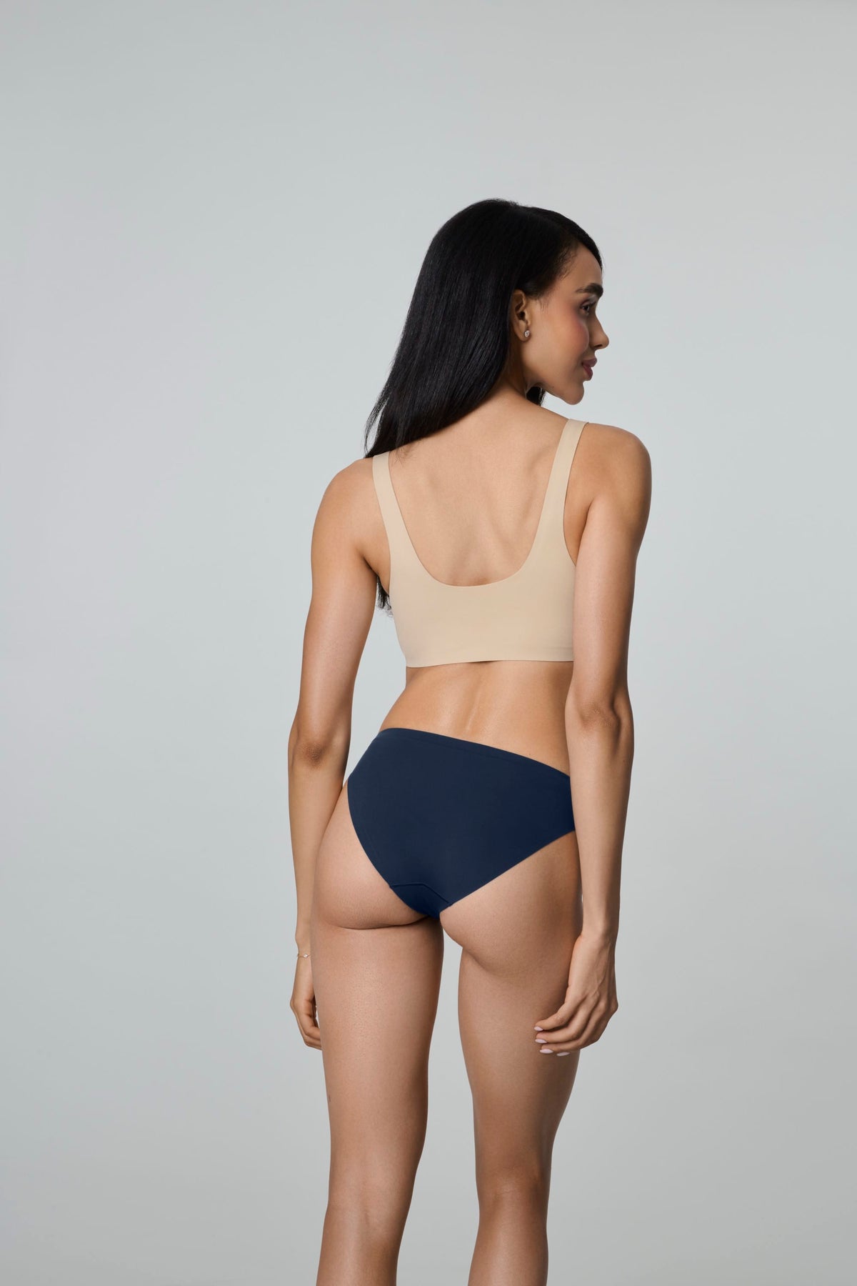 Daily Bikini in Navy, back view worn by a woman looking over her shoulder, showing the bikini brief coverage