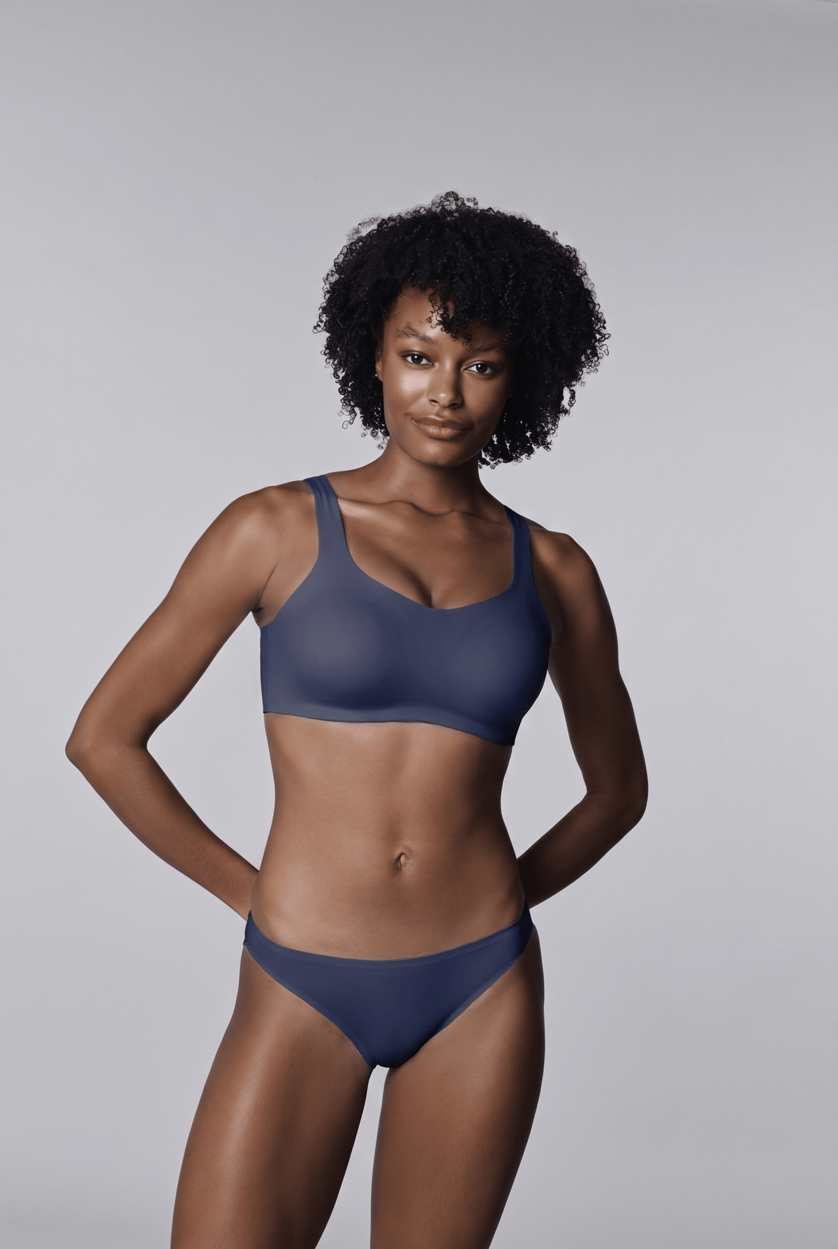 Daily Embrace in Navy, front view worn by a woman with short curly hair, hands behind her back, with matching briefs